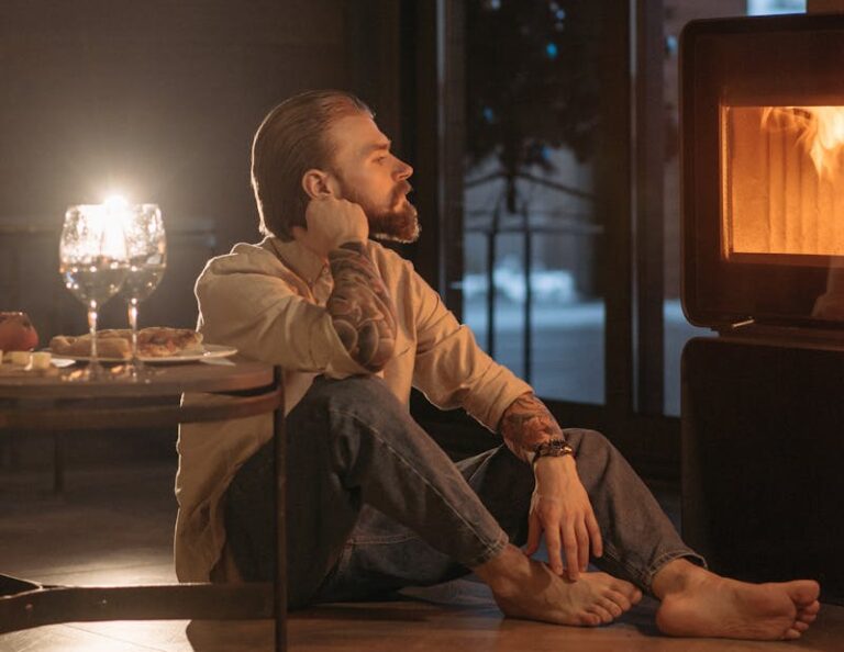 Zamyślony mężczyzna siedzi przy kominku w zimny zimowy wieczór